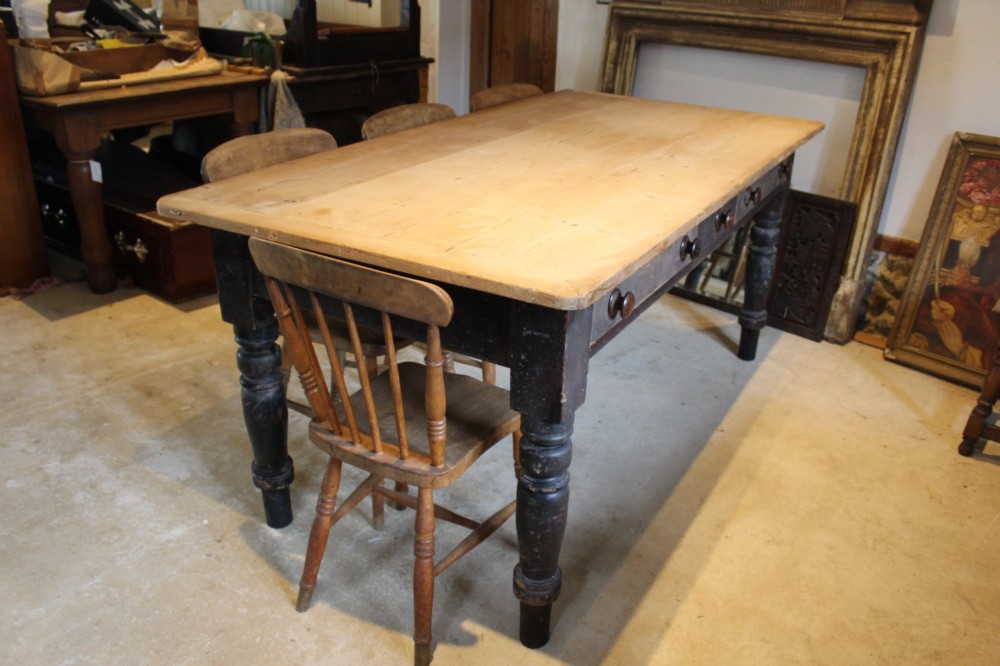 A 19th-century pine farmhouse dining table featuring a natural scrubbed wooden top, frieze drawers with round wooden knobs, and turned dark painted legs. View III
