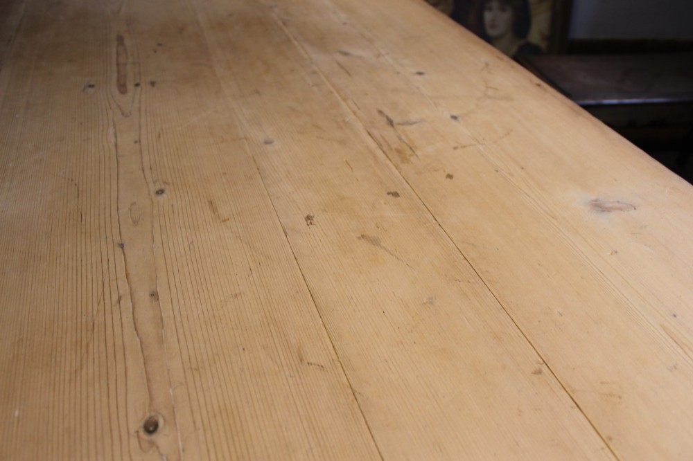 A 19th-century pine farmhouse dining table featuring a natural scrubbed wooden top, frieze drawers with round wooden knobs, and turned dark painted legs. View V