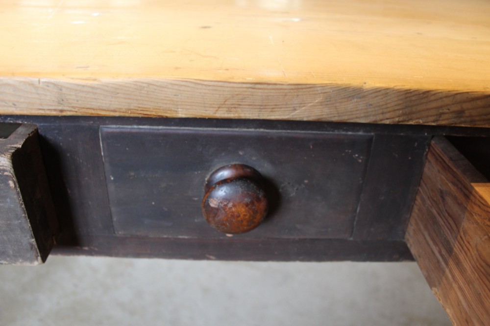 A 19th-century pine farmhouse dining table featuring a natural scrubbed wooden top, frieze drawers with round wooden knobs, and turned dark painted legs. View IX