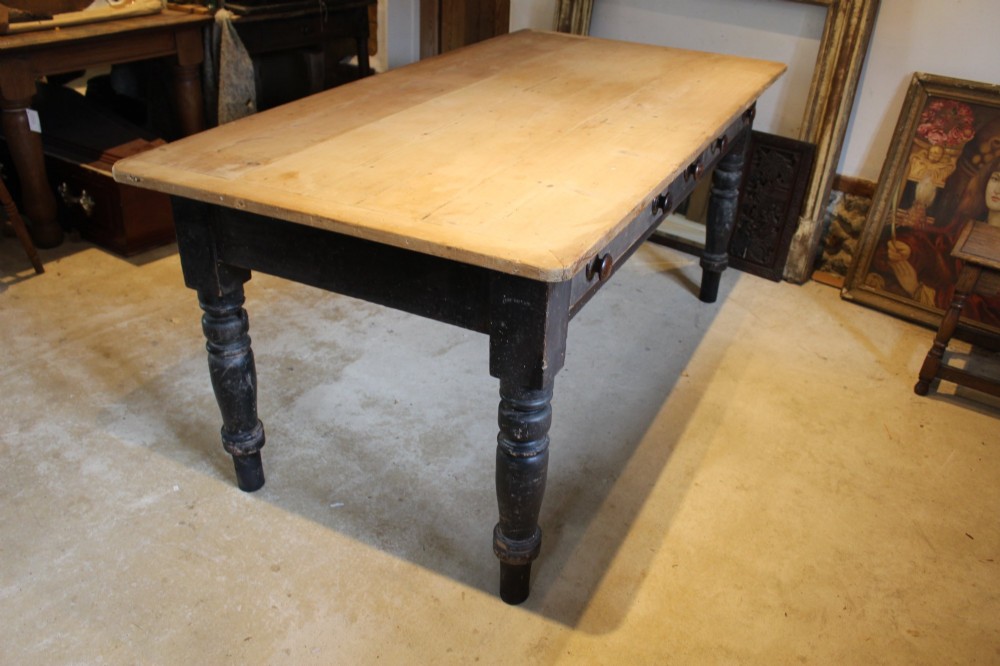 A 19th-century pine farmhouse dining table featuring a natural scrubbed wooden top, frieze drawers with round wooden knobs, and turned dark painted legs. View XI