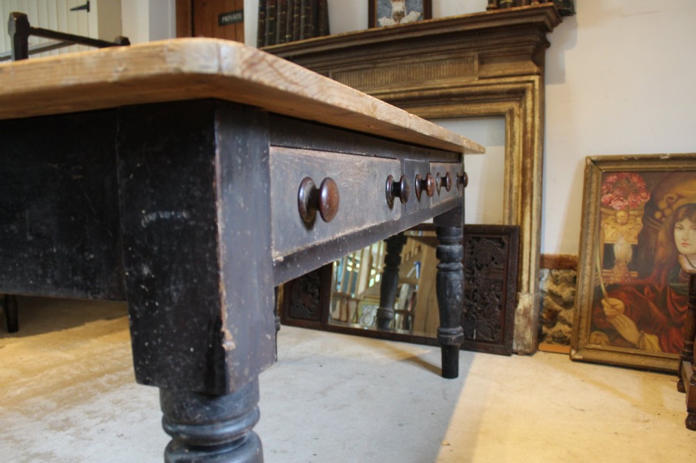 A 19th-century pine farmhouse dining table featuring a natural scrubbed wooden top, frieze drawers with round wooden knobs, and turned dark painted legs. View XIV