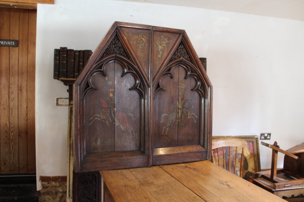 A pair of arched dark oak architectural panels featuring carved Gothic tracery and polychrome paintings of mounted medieval knights and heraldic shields.