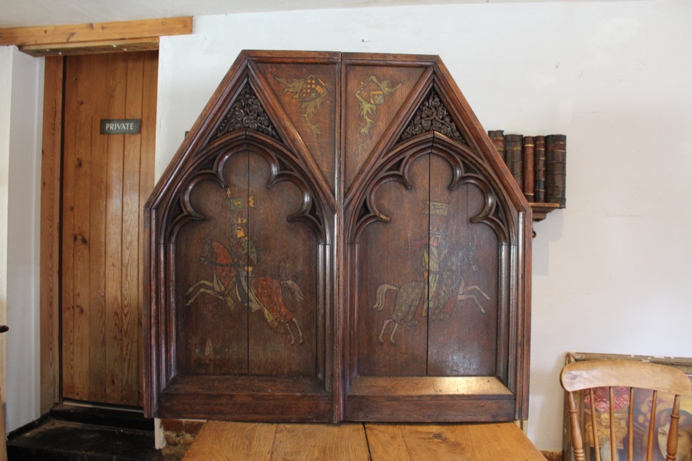 A pair of arched dark oak architectural panels featuring carved Gothic tracery and polychrome paintings of mounted medieval knights and heraldic shields. View II