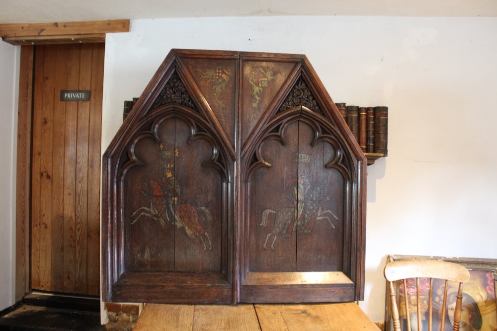 A pair of arched dark oak architectural panels featuring carved Gothic tracery and polychrome paintings of mounted medieval knights and heraldic shields. View X