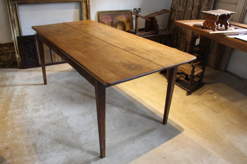 An antique French oak refectory dining table featuring a solid two-plank top, a side frieze drawer, and square tapered legs. View XI
