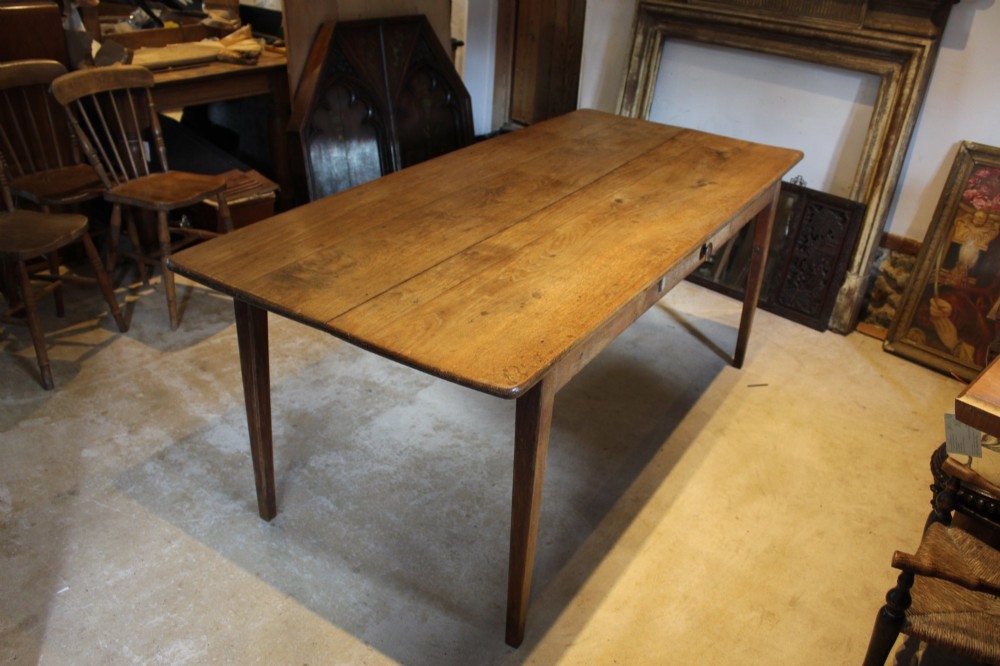 An antique French oak refectory dining table featuring a solid two-plank top, a side frieze drawer, and square tapered legs. View XIII