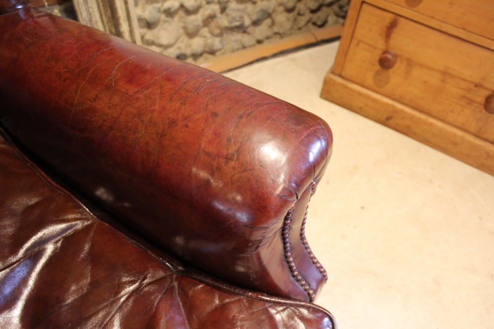 A late Victorian deep-buttoned chestnut brown leather wingback armchair featuring brass studding, carved front legs with ball-and-claw feet, and metal castors. View VII