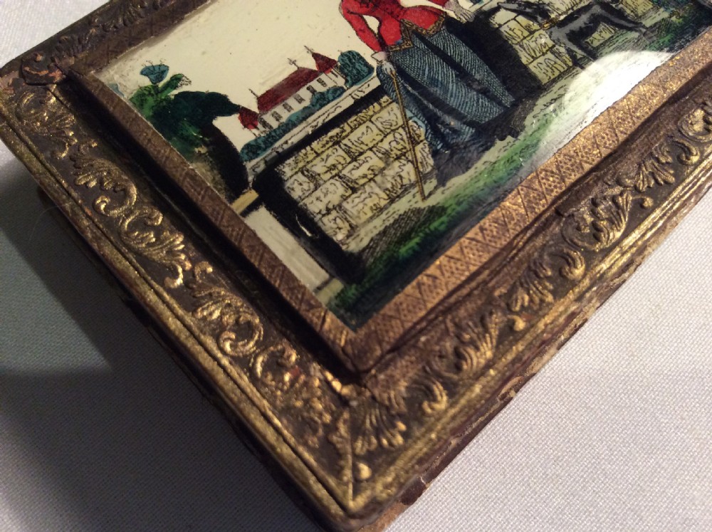 A rectangular 19th-century French bonbon box featuring gilded embossed paper borders and a glass inset lid depicting a miniature outdoor scene. View II