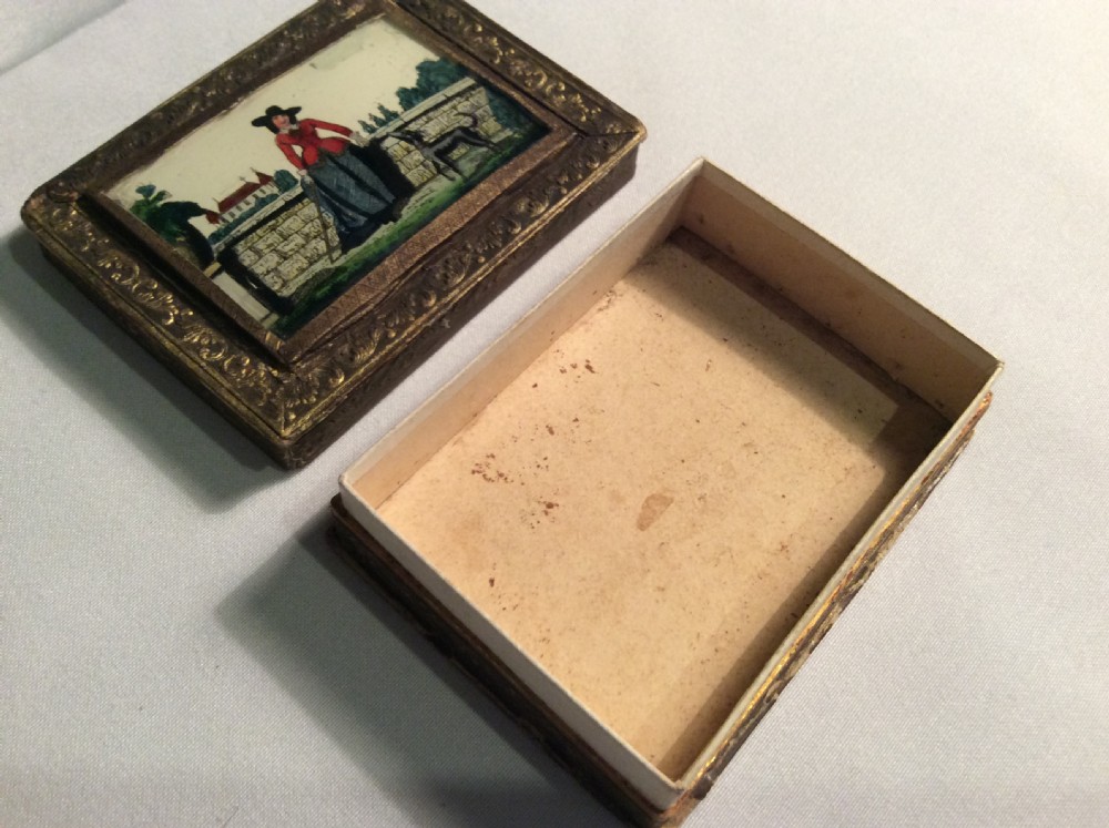 A rectangular 19th-century French bonbon box featuring gilded embossed paper borders and a glass inset lid depicting a miniature outdoor scene. View III