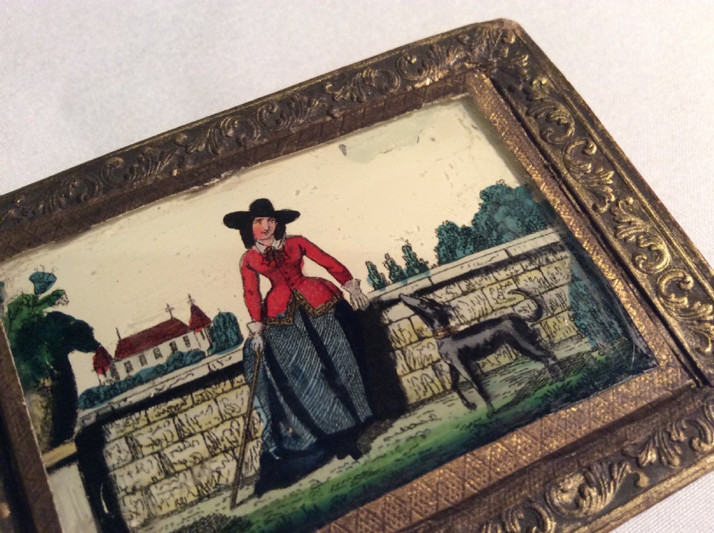 A rectangular 19th-century French bonbon box featuring gilded embossed paper borders and a glass inset lid depicting a miniature outdoor scene. View IV