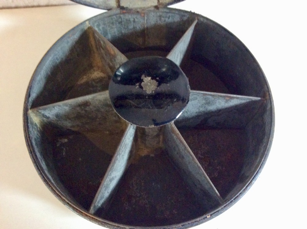 A circular black toleware spice box featuring a domed lid, brass top ring handle, gold accent band, and front metal latch. View VI