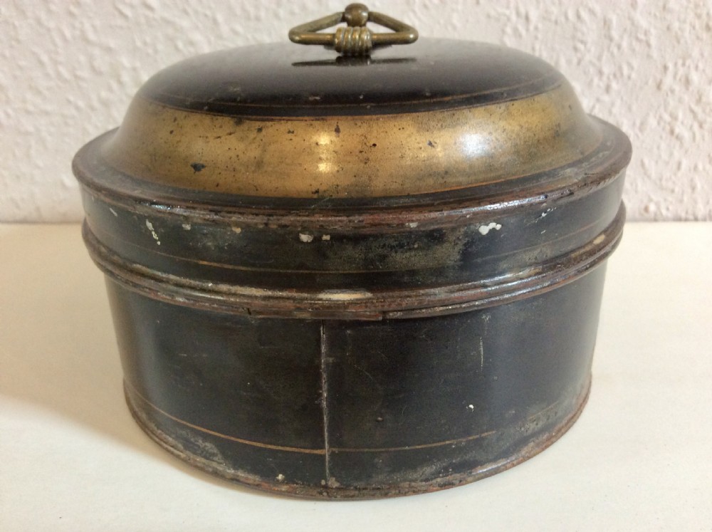 A circular black toleware spice box featuring a domed lid, brass top ring handle, gold accent band, and front metal latch. View IX