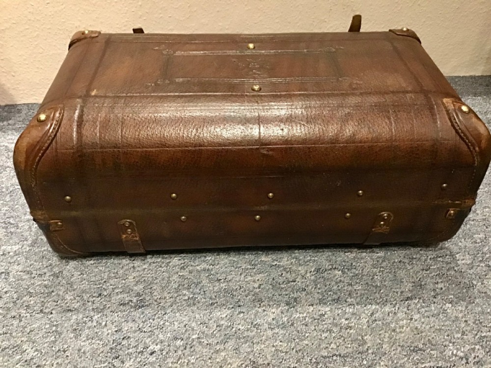An antique dark brown leather valise suitcase featuring brass hardware, stitched straps, and embossed geometric detailing. View VIII