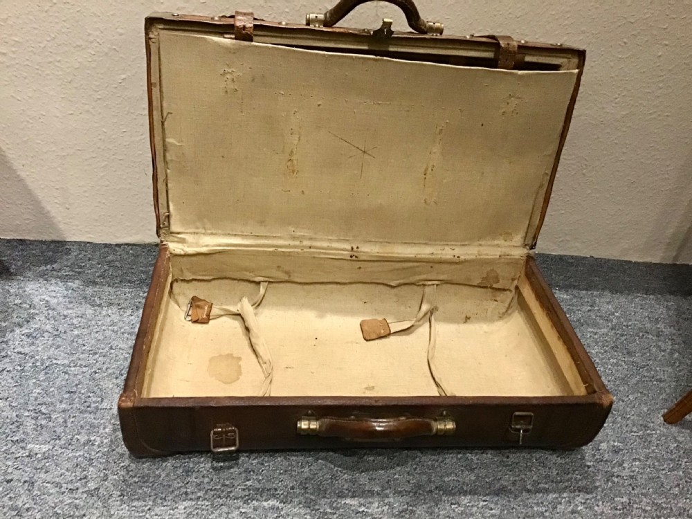 An antique dark brown leather valise suitcase featuring brass hardware, stitched straps, and embossed geometric detailing. View XI