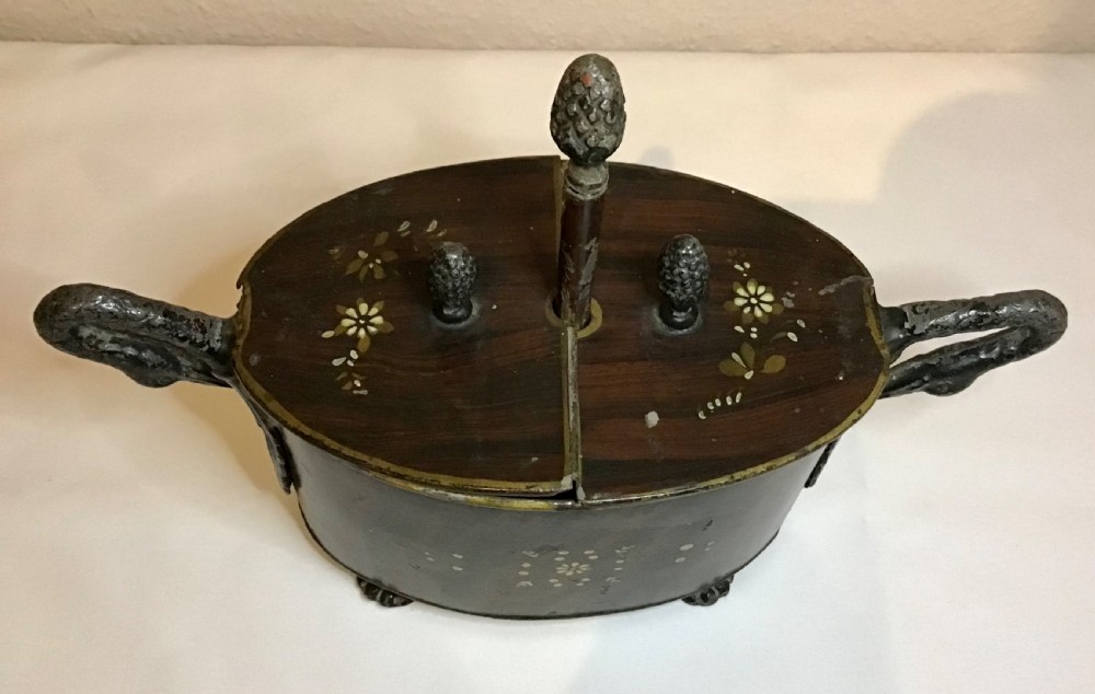 A dark brown oval wooden egg coddler featuring floral bone inlay, side handles, four metal feet, and three pinecone finials on the split lid. View II