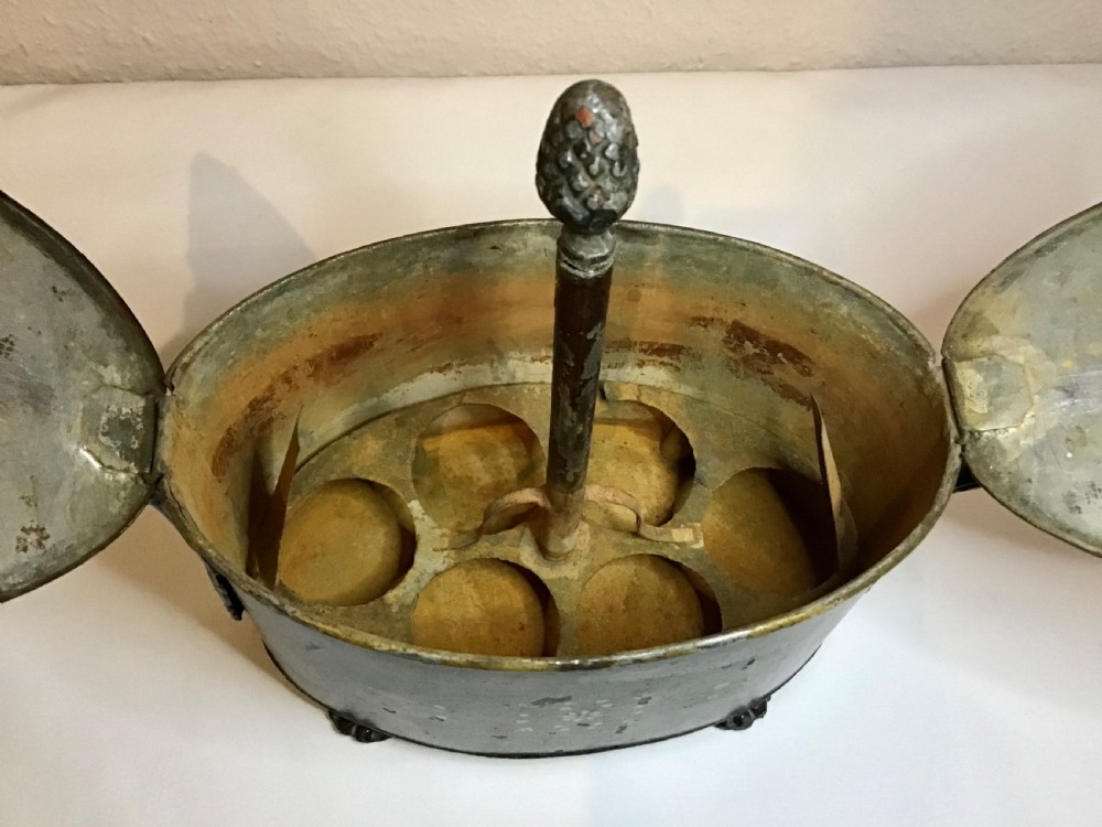 A dark brown oval wooden egg coddler featuring floral bone inlay, side handles, four metal feet, and three pinecone finials on the split lid. View VI