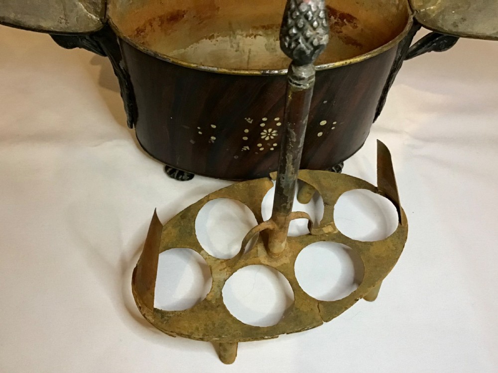 A dark brown oval wooden egg coddler featuring floral bone inlay, side handles, four metal feet, and three pinecone finials on the split lid. View IX