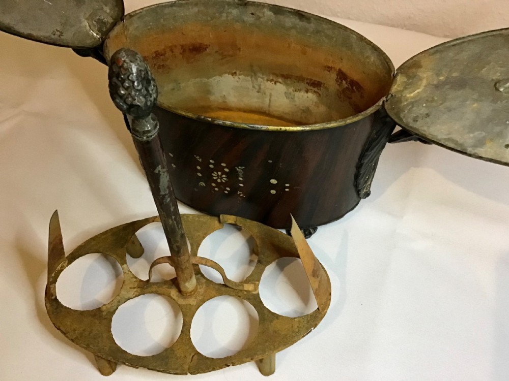 A dark brown oval wooden egg coddler featuring floral bone inlay, side handles, four metal feet, and three pinecone finials on the split lid. View XII
