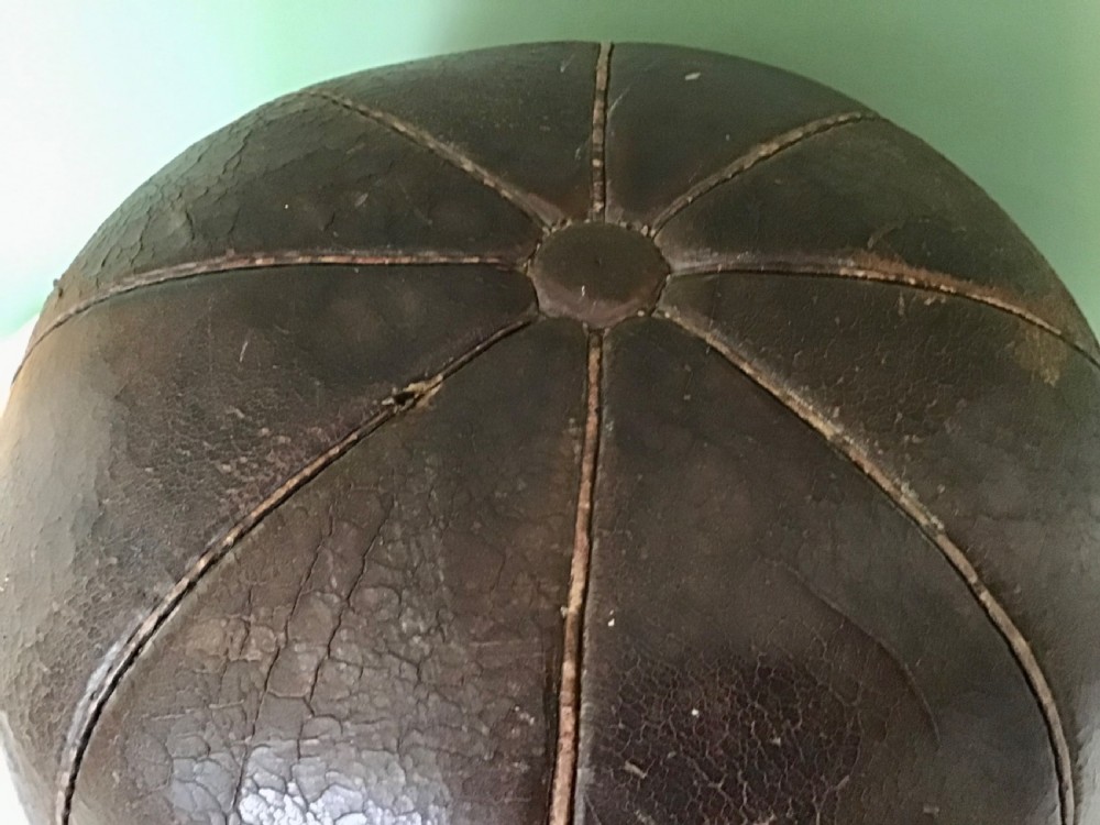 A spherical Edwardian medicine ball crafted from dark brown stitched leather panels displaying a weathered patina. View V