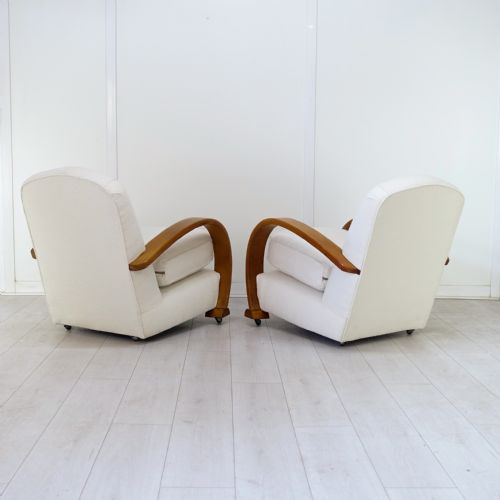 fig 2. A pair of 1930s Art Deco armchairs upholstered in cream textured fabric featuring sweeping bentwood wooden armrests and castors.
