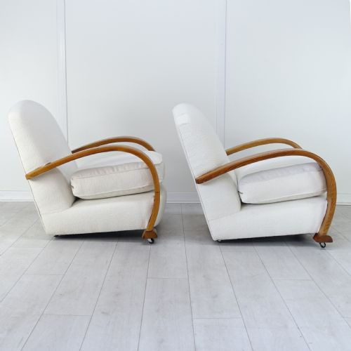 fig 4. A pair of 1930s Art Deco armchairs upholstered in cream textured fabric featuring sweeping bentwood wooden armrests and castors.