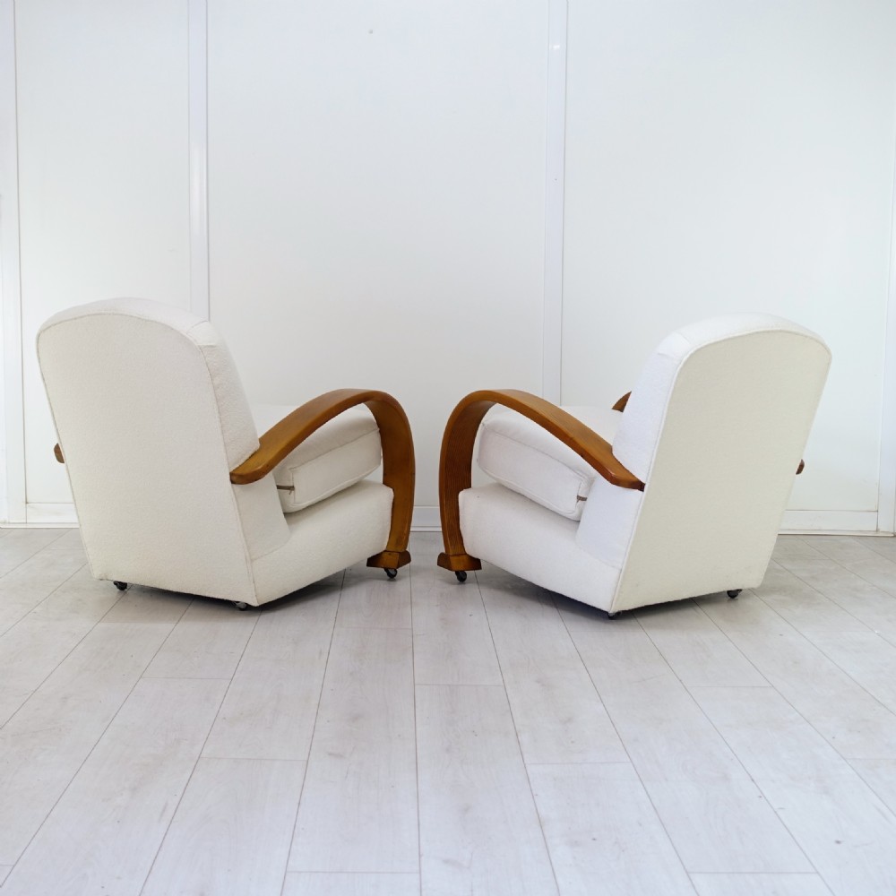 A pair of 1930s Art Deco armchairs upholstered in cream textured fabric featuring sweeping bentwood wooden armrests and castors. View III