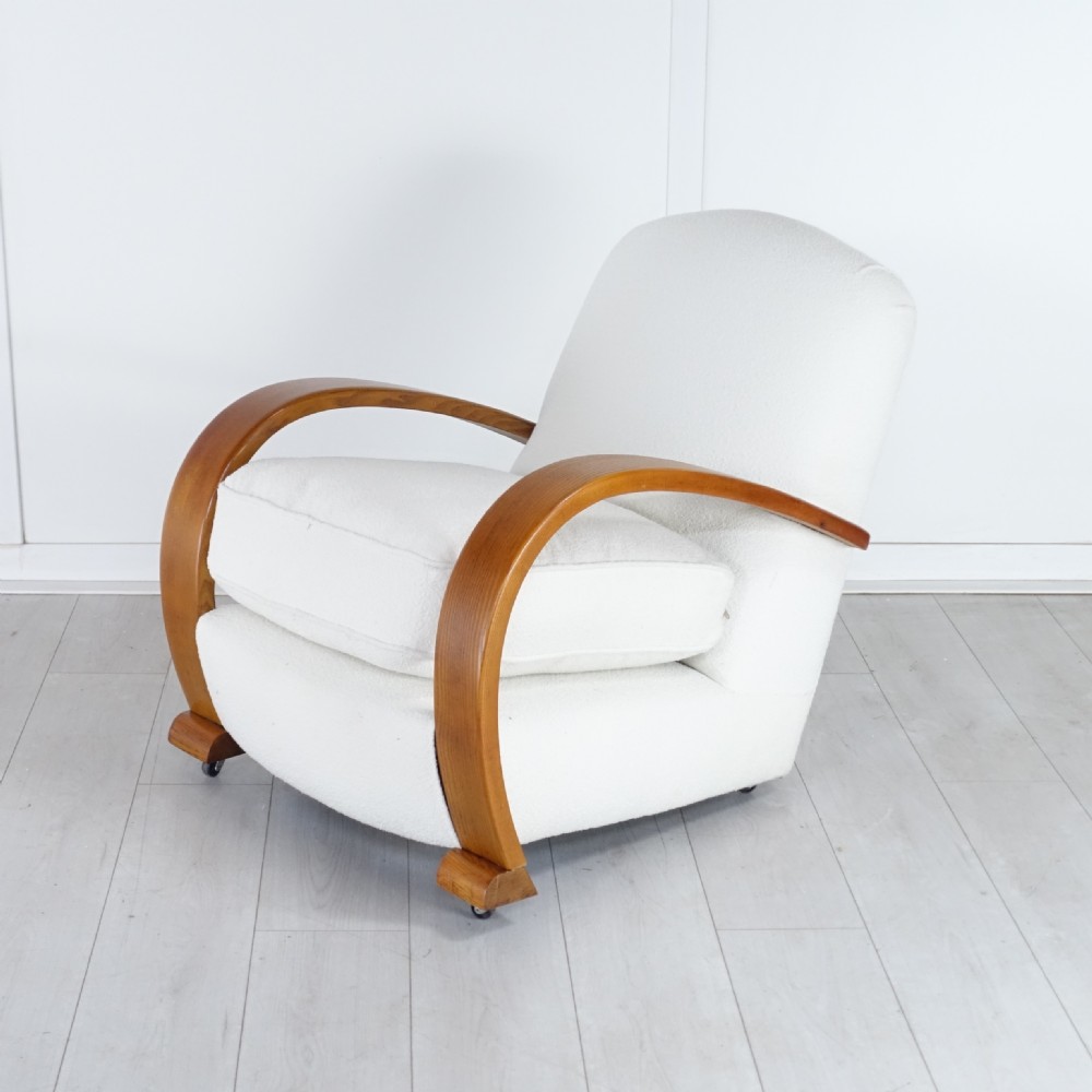 A pair of 1930s Art Deco armchairs upholstered in cream textured fabric featuring sweeping bentwood wooden armrests and castors. View VII