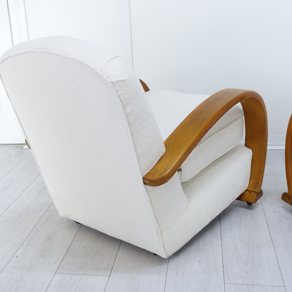 A pair of 1930s Art Deco armchairs upholstered in cream textured fabric featuring sweeping bentwood wooden armrests and castors. View IX
