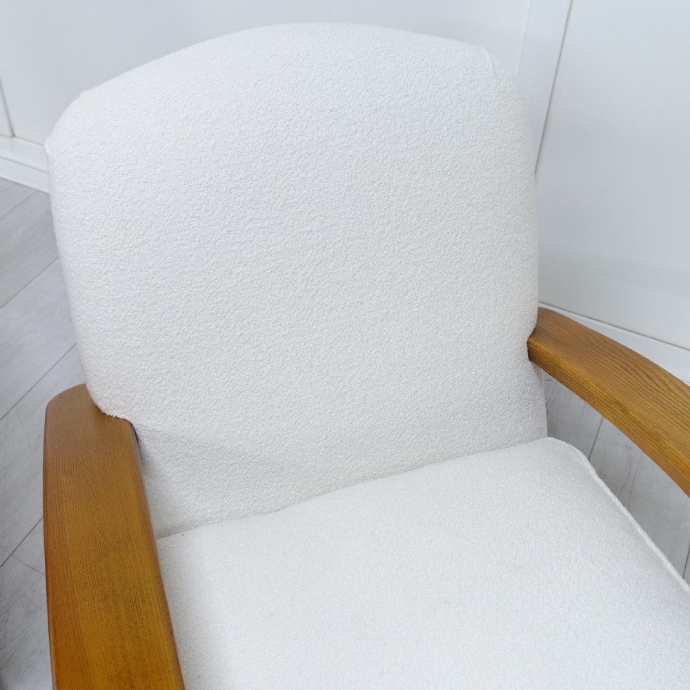 A pair of 1930s Art Deco armchairs upholstered in cream textured fabric featuring sweeping bentwood wooden armrests and castors. View X
