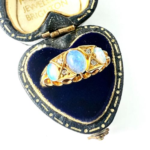 fig 1. A Victorian 18ct gold ring featuring three cabochon opals separated by diamond accents within a carved scroll setting.