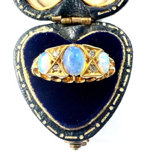 fig 2. A Victorian 18ct gold ring featuring three cabochon opals separated by diamond accents within a carved scroll setting.