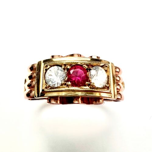 fig 1. A vintage 14ct yellow and rose gold ring featuring a central red ruby paste stone flanked by two clear stones in a rectangular box setting with scrollwork shoulders.