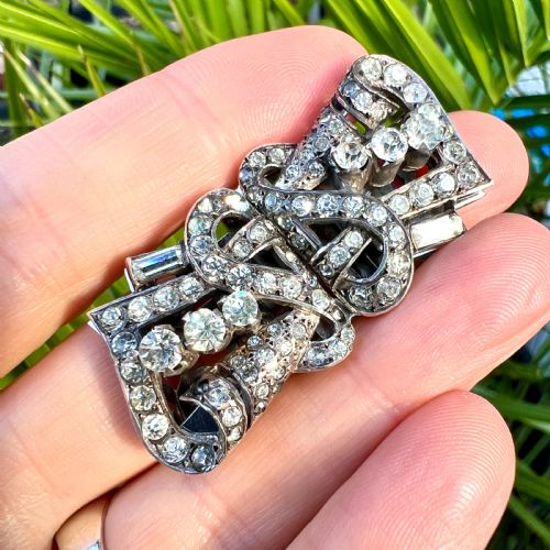 fig 1. An Art Deco silver-tone paste duette brooch featuring geometric scrollwork set with round and baguette cut clear paste stones.
