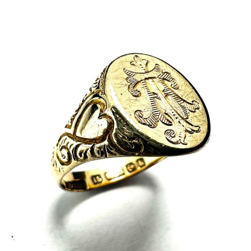 fig 1. An antique yellow gold signet ring featuring an oval head with a hand-engraved monogram and detailed heart motifs on the shoulders.