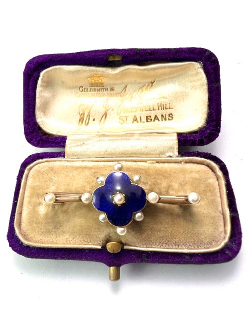 fig 1. An Edwardian gold bar brooch featuring a central quatrefoil motif decorated in cobalt blue guilloche enamel and surrounded by pearls.
