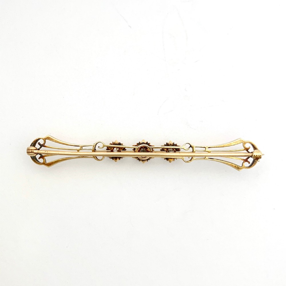 An Edwardian 14ct yellow gold bar brooch featuring three starburst-set diamonds along a openwork frame. View II