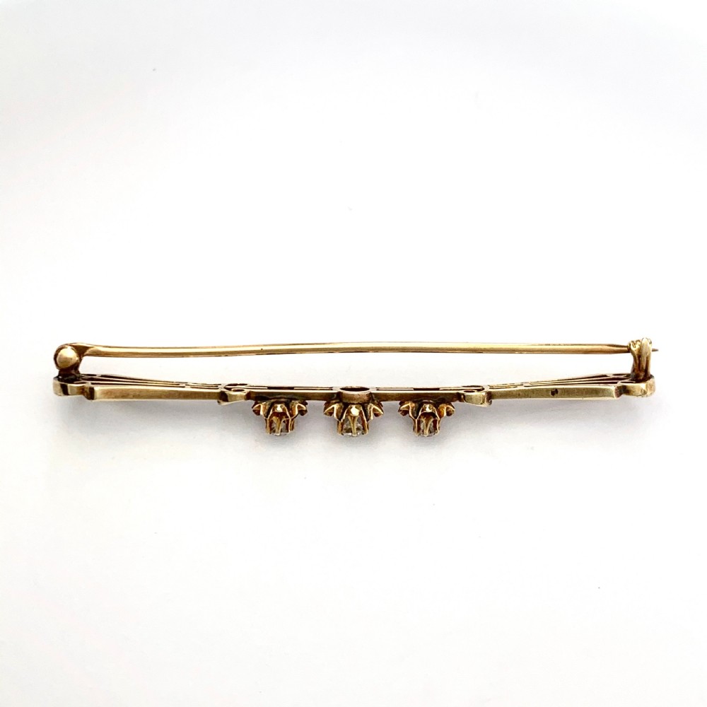 An Edwardian 14ct yellow gold bar brooch featuring three starburst-set diamonds along a openwork frame. View III