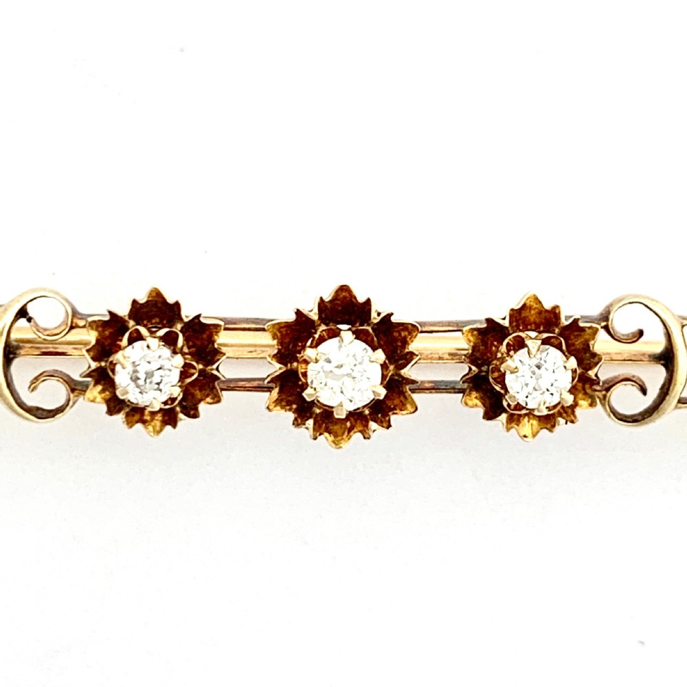 An Edwardian 14ct yellow gold bar brooch featuring three starburst-set diamonds along a openwork frame. View IV