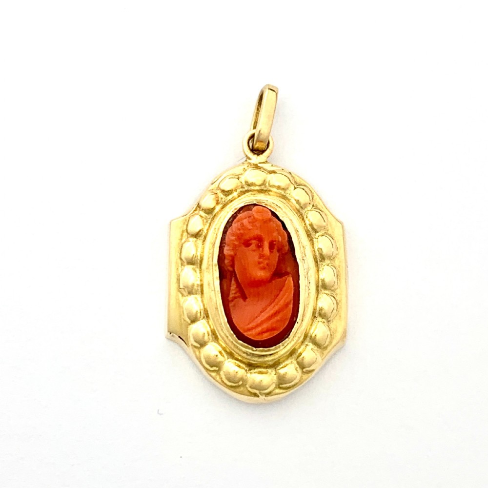 An oval Victorian 18ct gold pendant featuring an orange-red carved coral cameo classical bust framed by a beaded gold border.