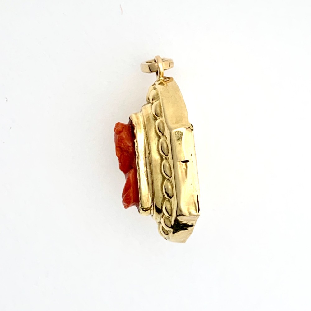 An oval Victorian 18ct gold pendant featuring an orange-red carved coral cameo classical bust framed by a beaded gold border. View III