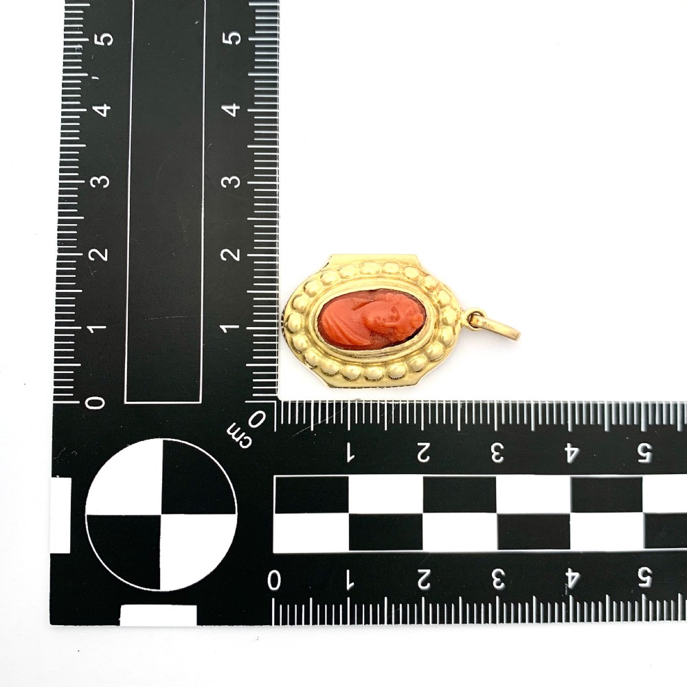 An oval Victorian 18ct gold pendant featuring an orange-red carved coral cameo classical bust framed by a beaded gold border. View VII