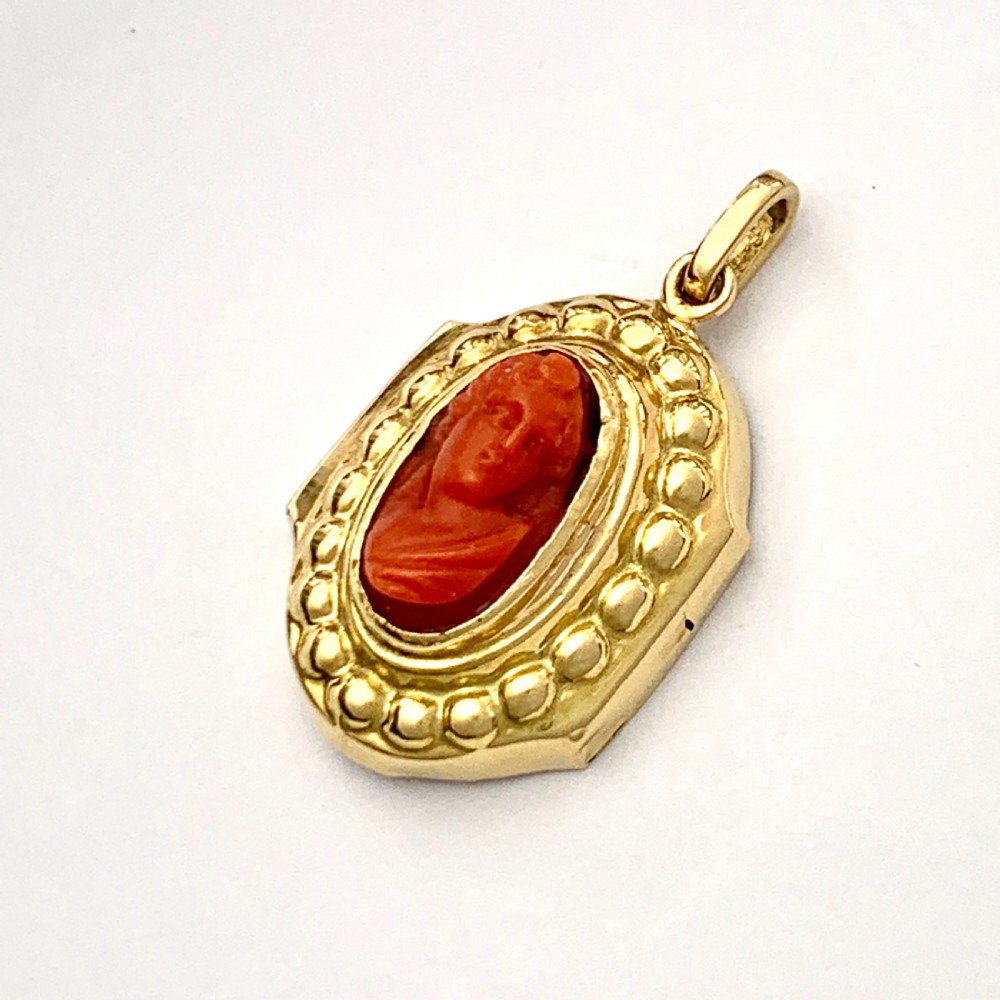 An oval Victorian 18ct gold pendant featuring an orange-red carved coral cameo classical bust framed by a beaded gold border. View VIII