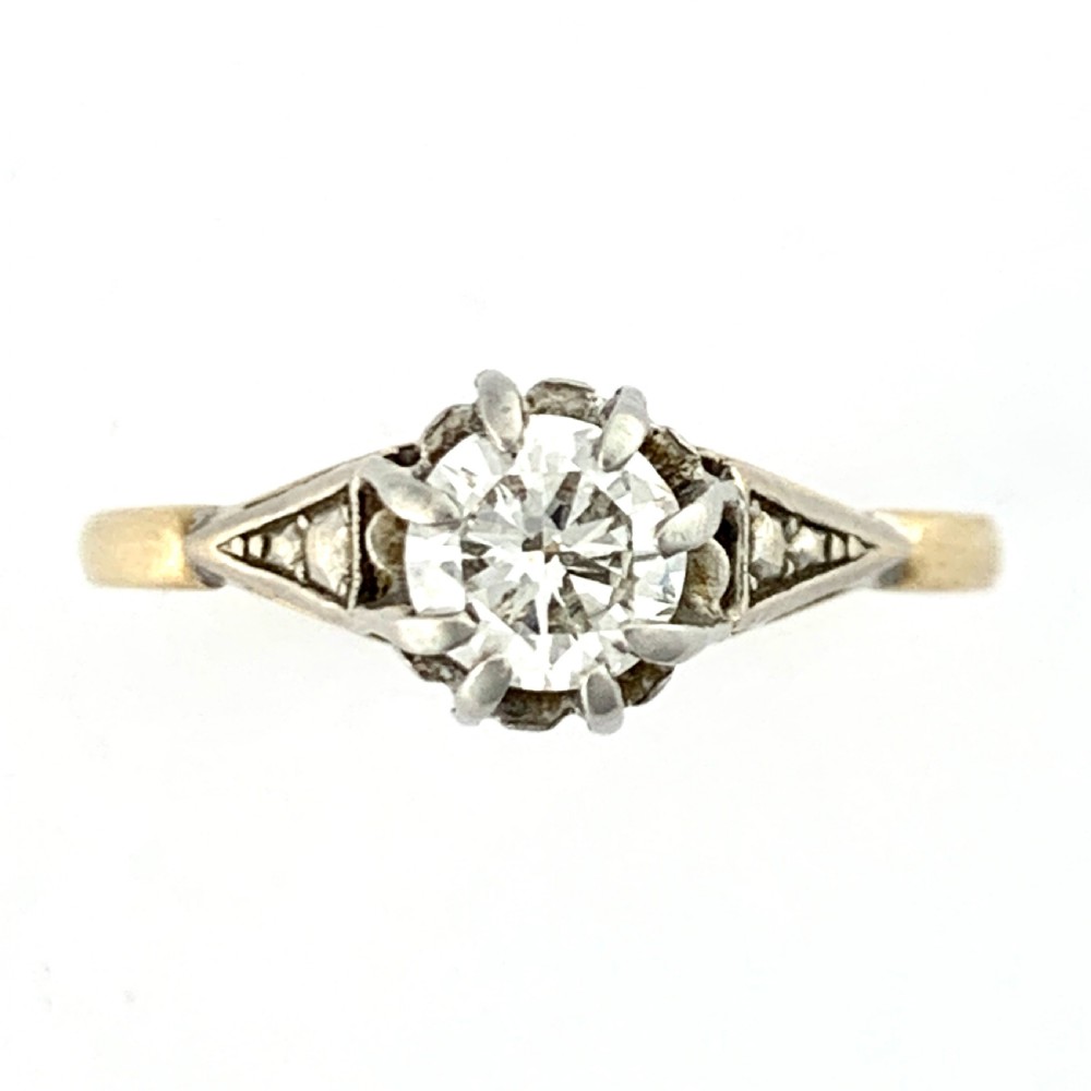 A vintage 18ct yellow gold solitaire ring displaying a single round diamond held in platinum claws with geometric shoulders.