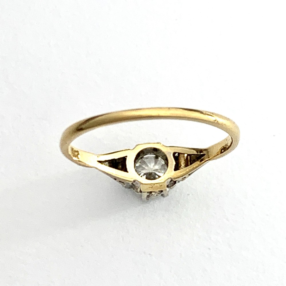 A vintage 18ct yellow gold solitaire ring displaying a single round diamond held in platinum claws with geometric shoulders. View II