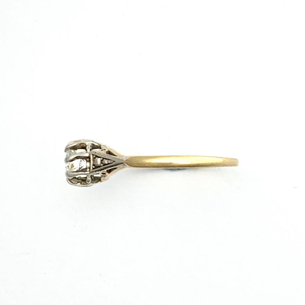 A vintage 18ct yellow gold solitaire ring displaying a single round diamond held in platinum claws with geometric shoulders. View V