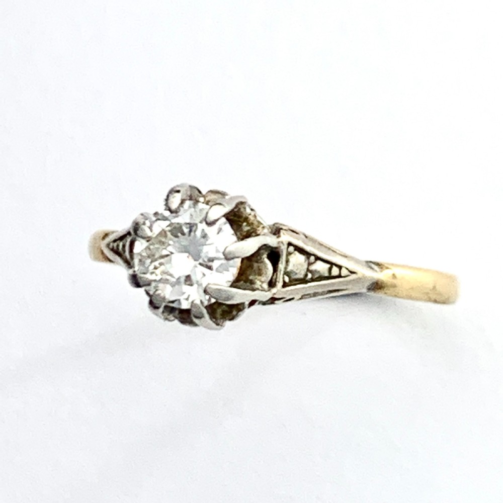 A vintage 18ct yellow gold solitaire ring displaying a single round diamond held in platinum claws with geometric shoulders. View VI