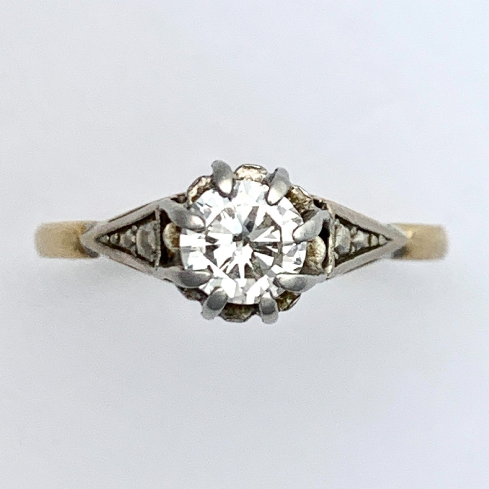 A vintage 18ct yellow gold solitaire ring displaying a single round diamond held in platinum claws with geometric shoulders. View VII