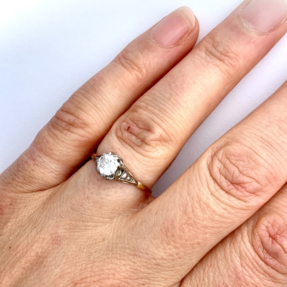A vintage 18ct yellow gold solitaire ring displaying a single round diamond held in platinum claws with geometric shoulders. View VIII