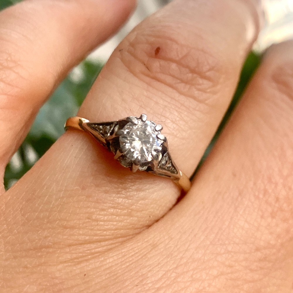 A vintage 18ct yellow gold solitaire ring displaying a single round diamond held in platinum claws with geometric shoulders. View IX