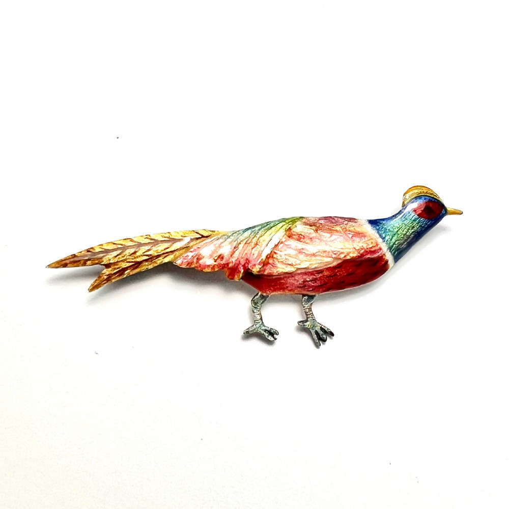 An Art Deco silver brooch shaped like a standing pheasant featuring red, green, blue, and gold enamel detailing.